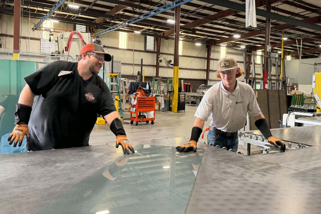 Two Glass Plant Workers Moving Glass On A Table